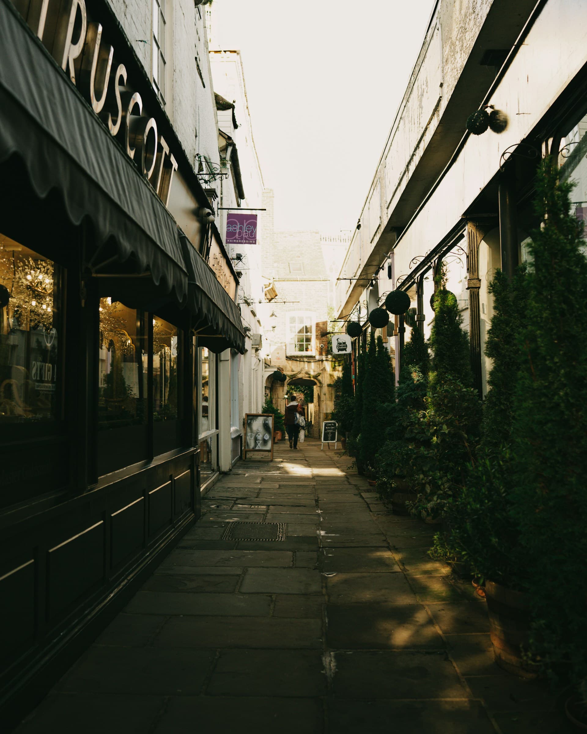 Narrow pedestrian lane with shopfronts, strong perspective, and a distant figure